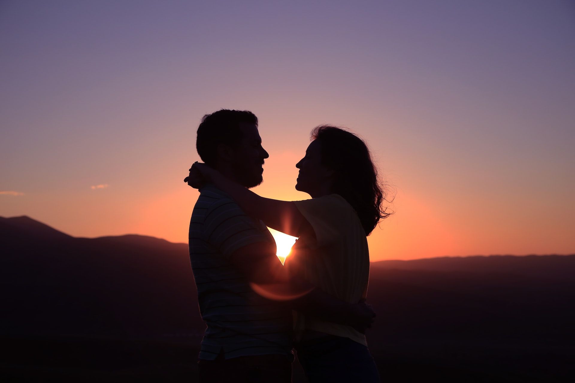 Man and woman with arms around each other at sunset.